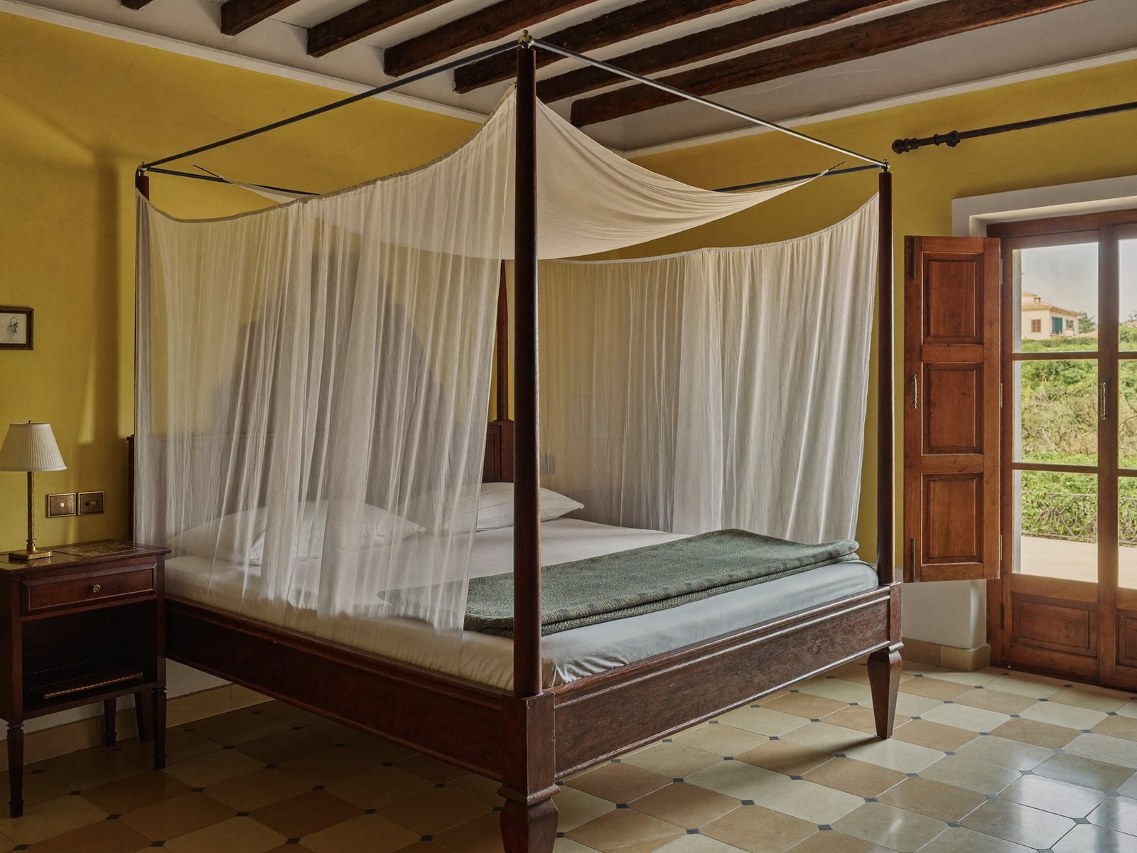 The Courtyard Suite with an antique four-poster bed, muslin canopy and doors opening to the courtyard